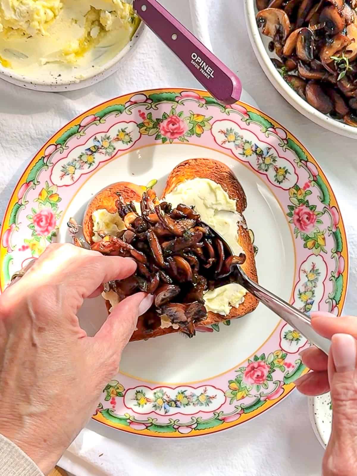 Spooning mushrooms on top of toast that has been spread with a cheesy mascarpone.