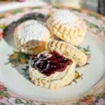 British cream scone with clotted cream and jam on a floral plate.