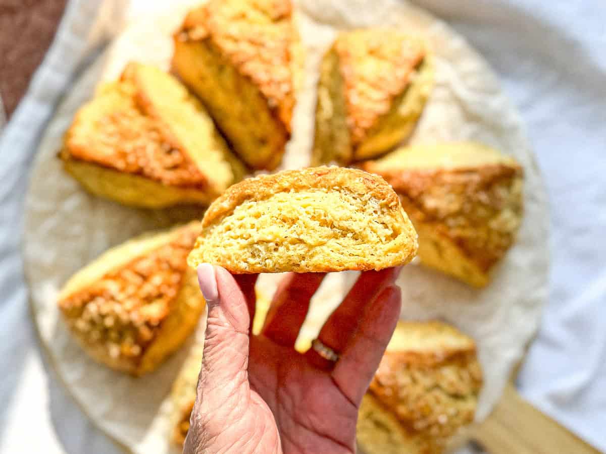 Author's hand holding, a buttermilk scone, showing the side and all of its layers.