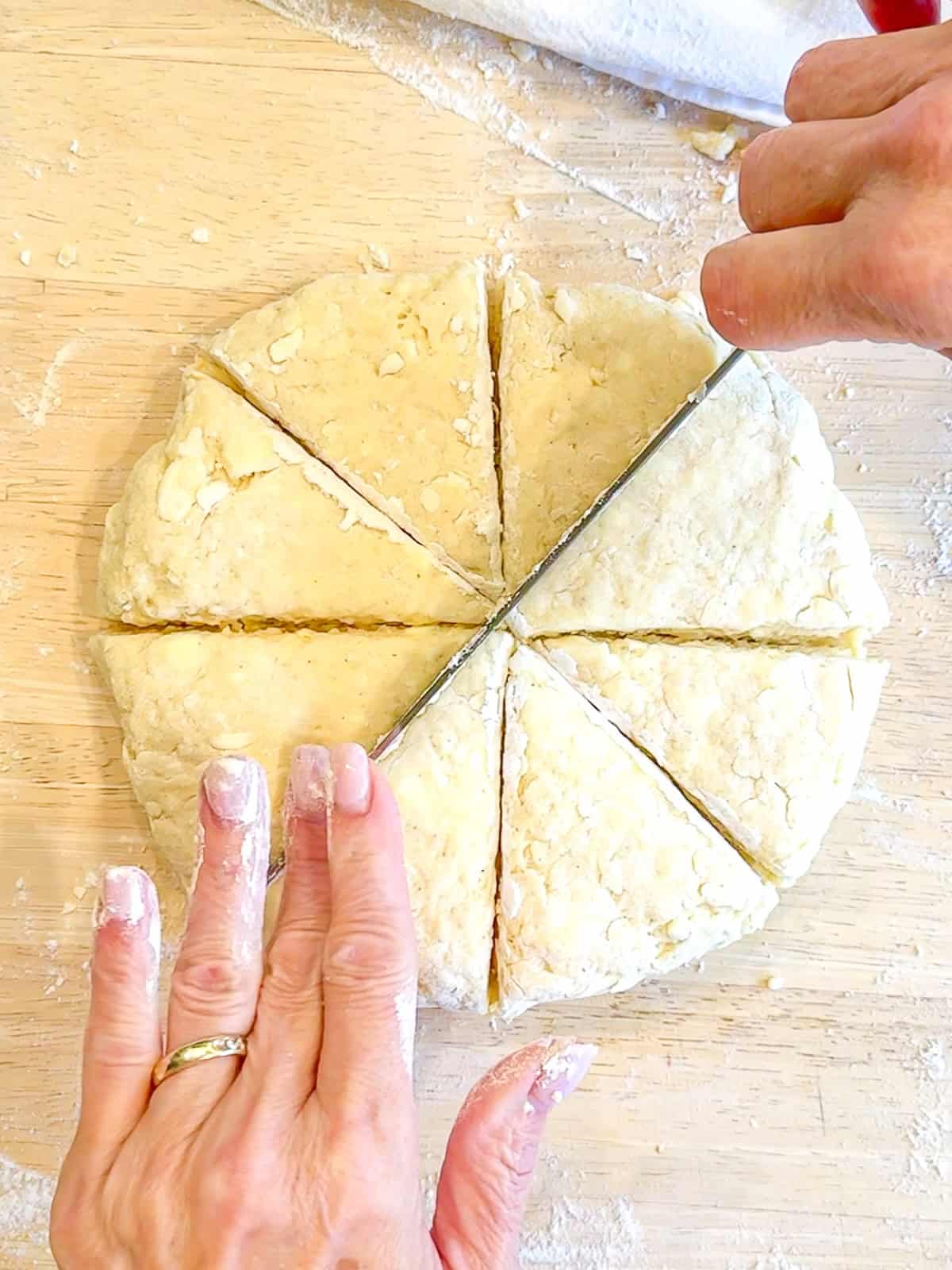 Using a sharp knife to cut a disk of buttermilk scone dough into eight wedges.