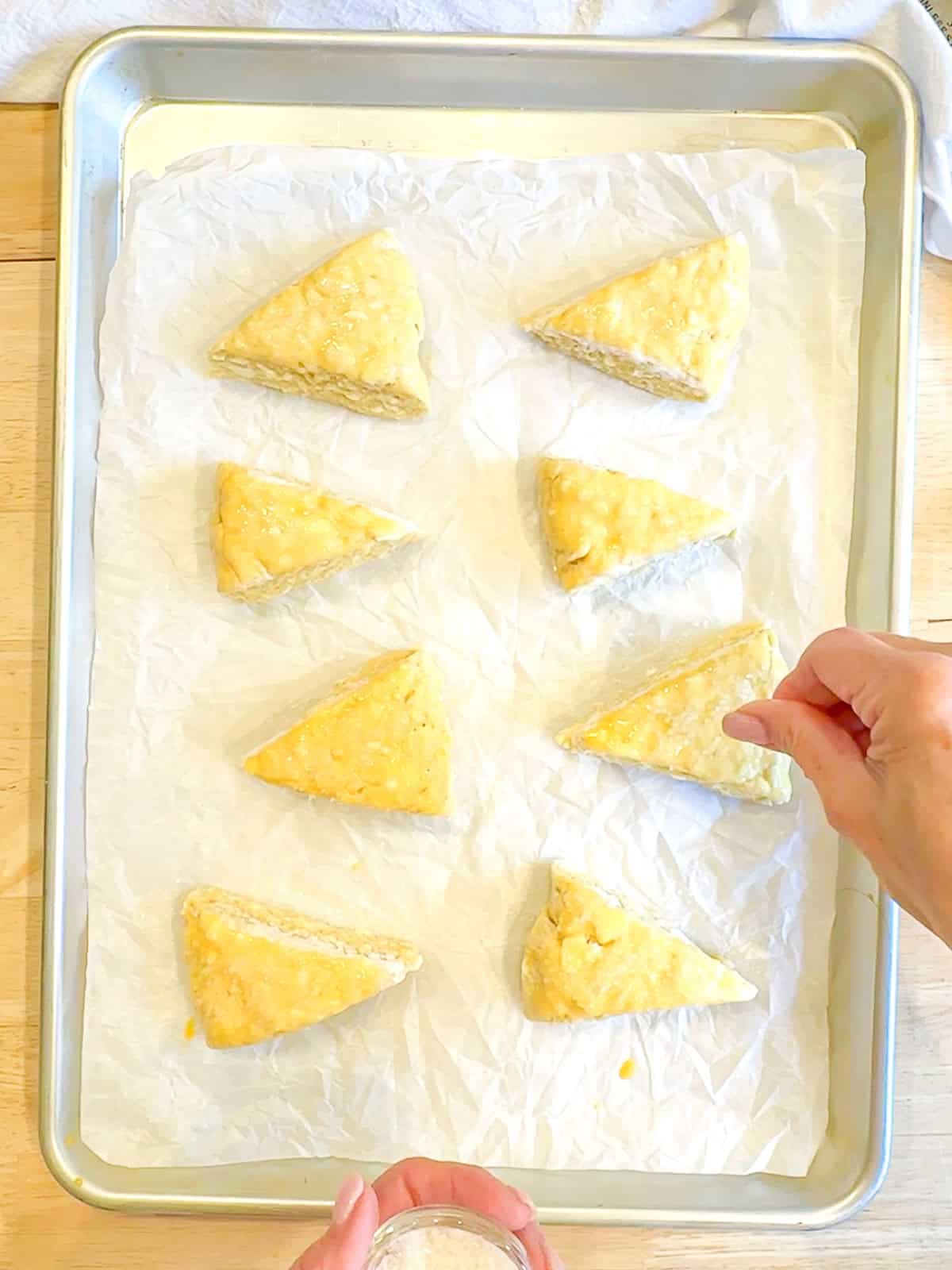 Sprinkling sparkling sugar on top of unbaked, buttermilk scones.