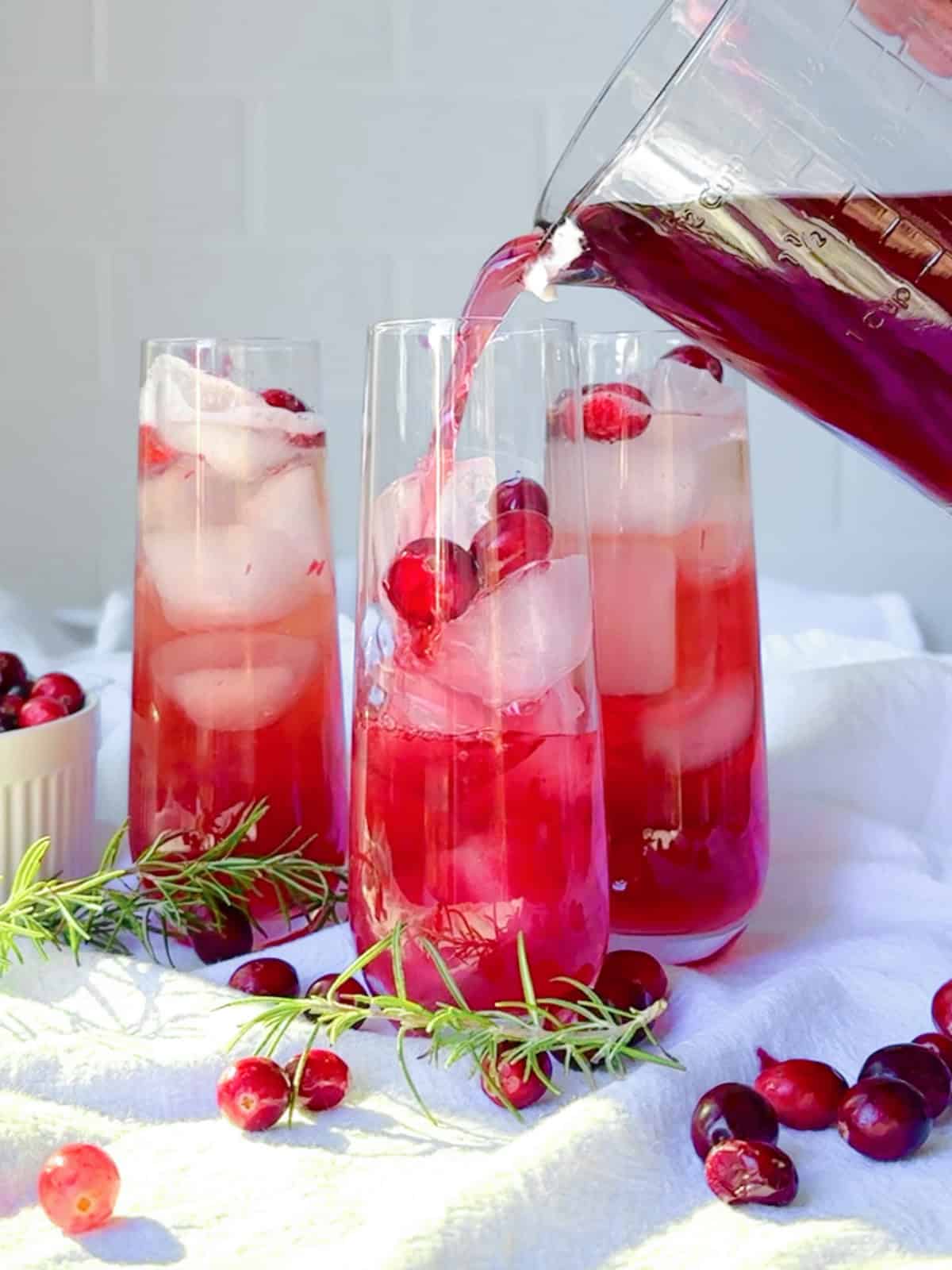 Pouring unsweetened cranberry juice for a cranberry mocktail.