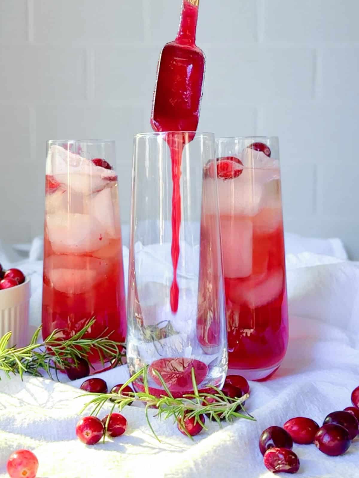 Adding pureed cranberry sauce to a glass to make a cranberry mocktail.