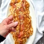 Author's hand holding a bacon pancake.