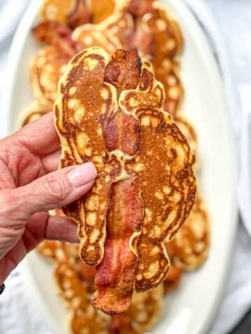 Author's hand holding a bacon pancake.