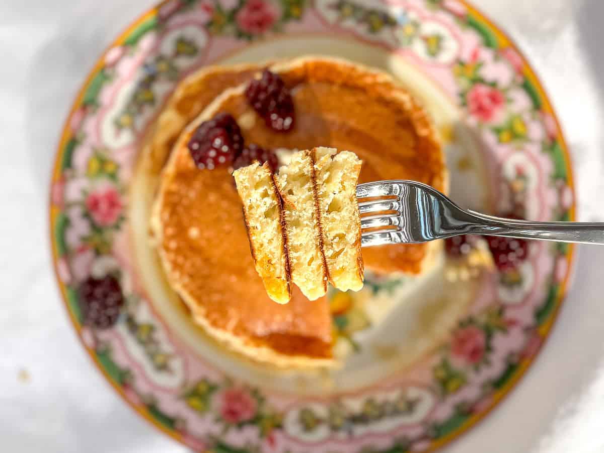 Fork holding a bite of pancakes, showing the fluffy interior.