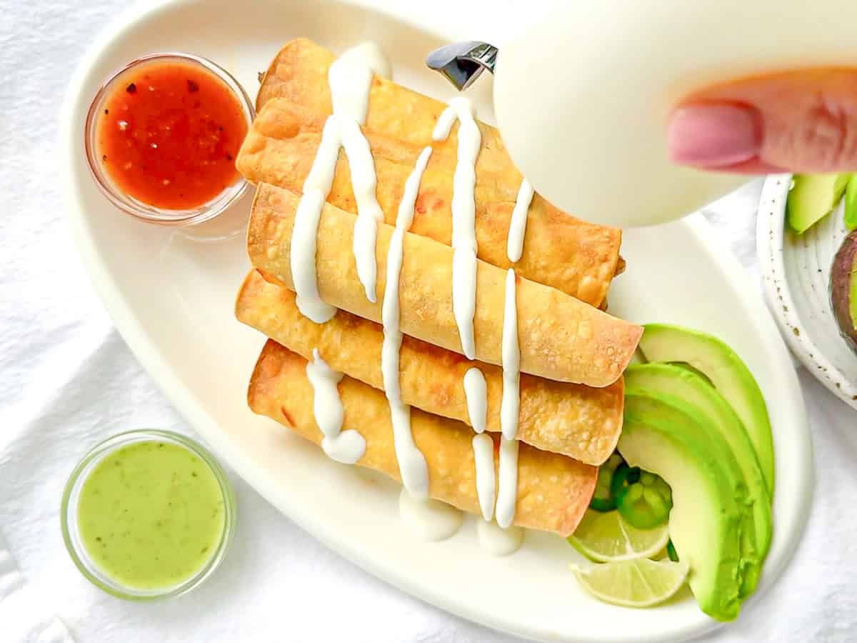 Drizzling lime crema on top of baked breakfast taquitos