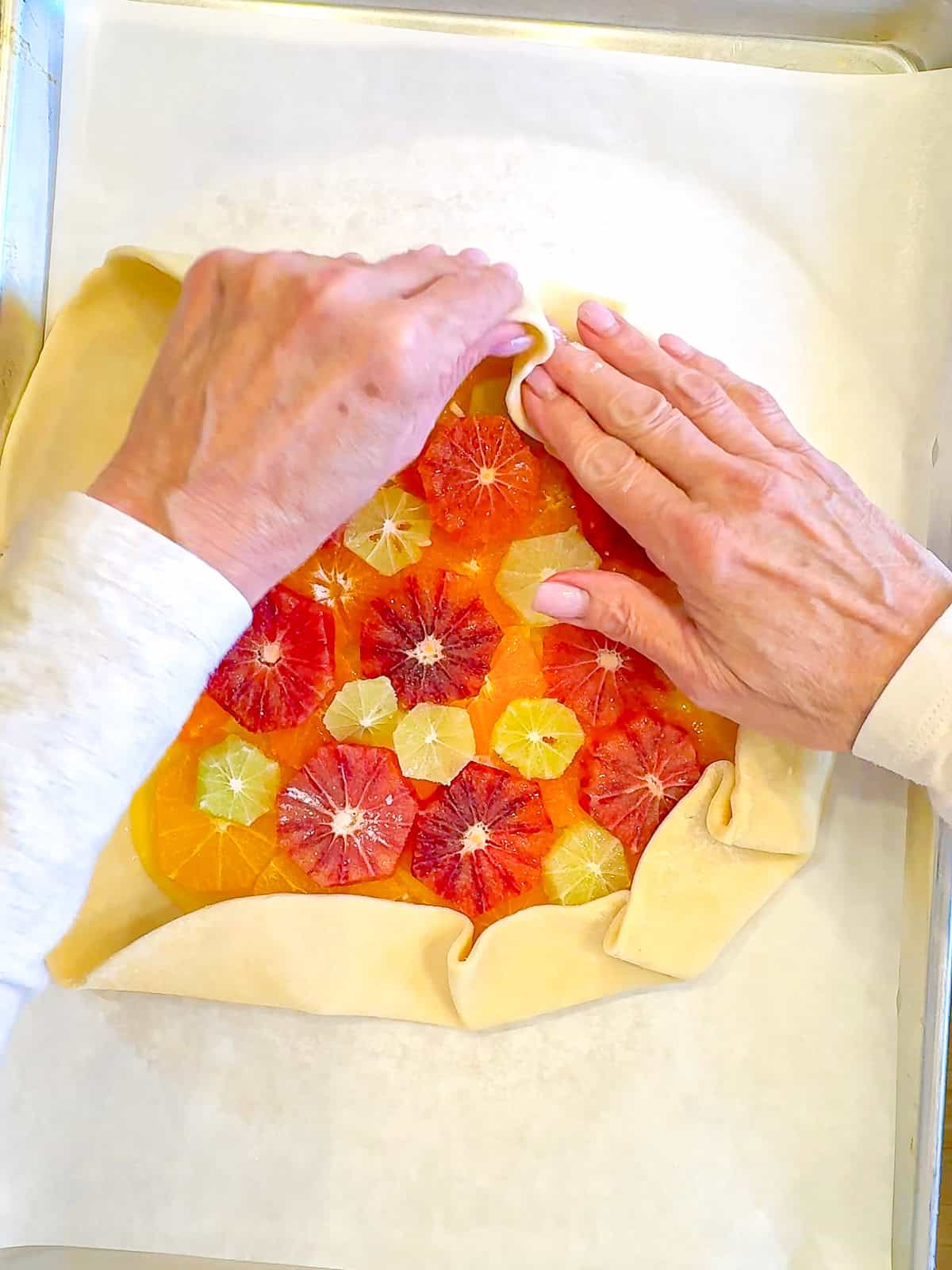 Folding up the edges of the crust over the citrus filling.