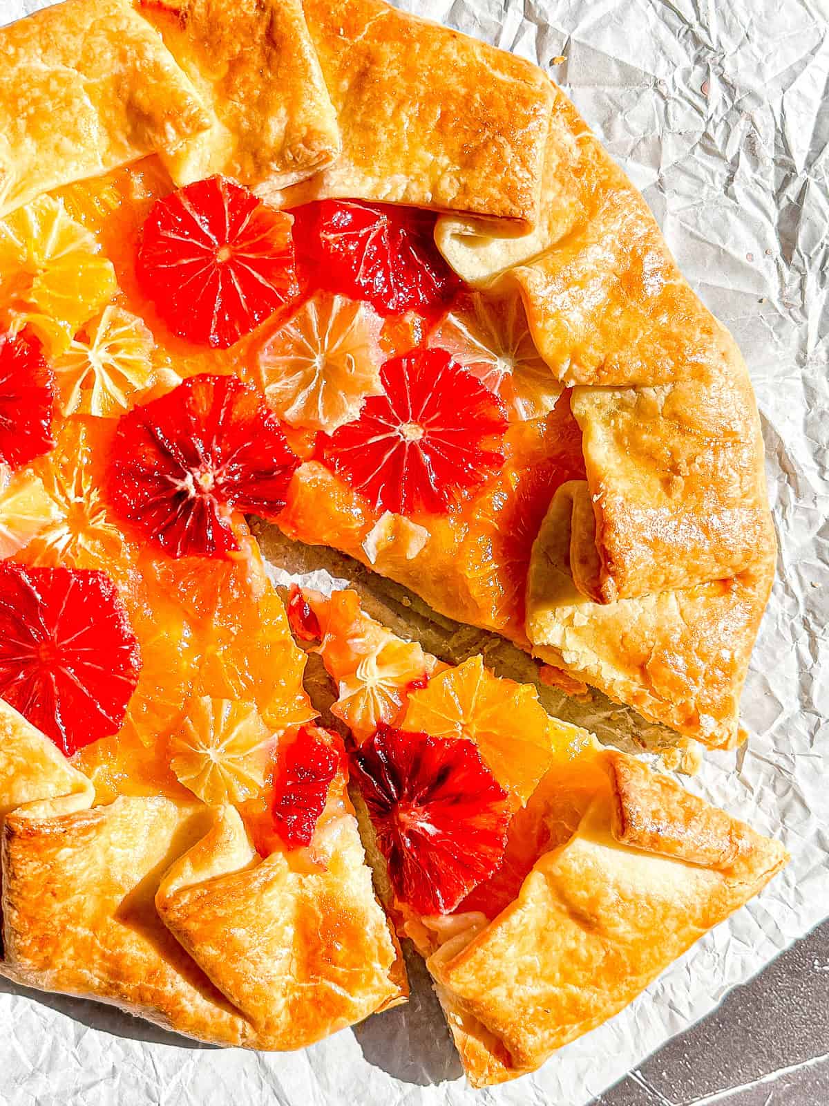 Citrus Galette with a slice taken out on a piece of parchment paper.