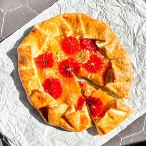 Citrus Galette with a slice taken out on a piece of parchment paper.