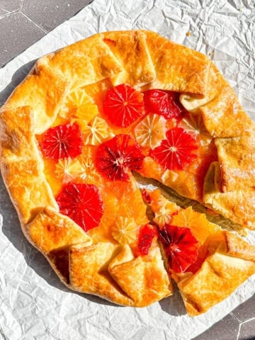 Citrus Galette with a slice taken out on a piece of parchment paper.