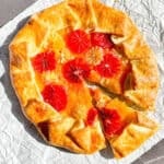 Citrus Galette with a slice taken out on a piece of parchment paper.