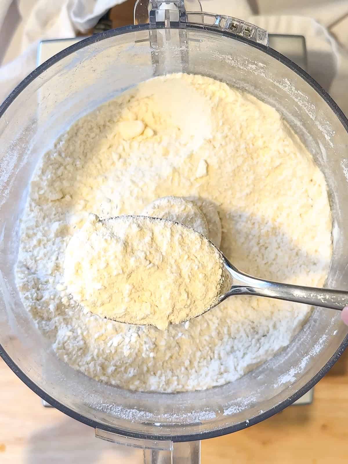 A spoon holding flour mixture with butter and cream cheese cut in.