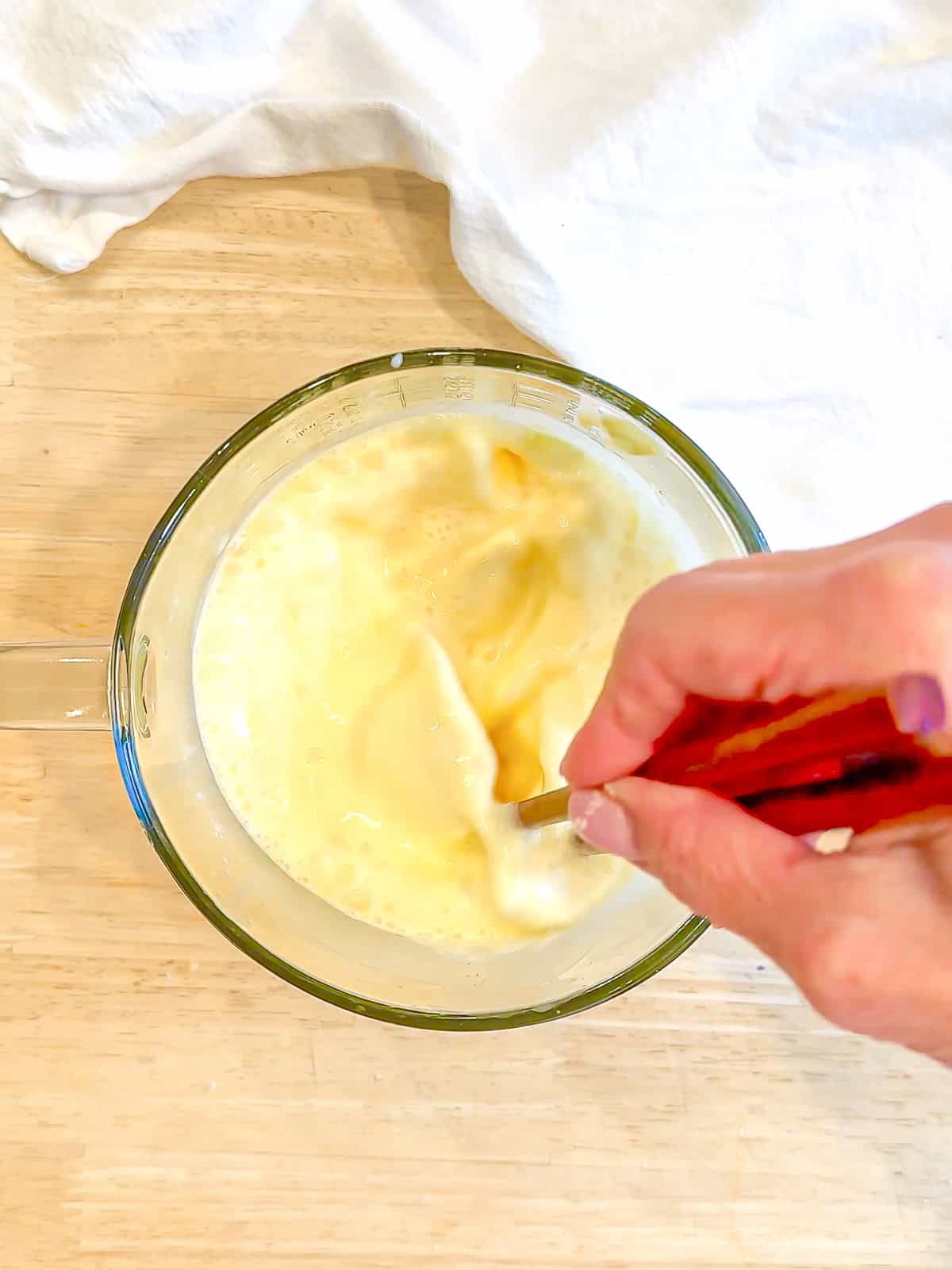 Whisking together milk, egg, and vanilla to make a classic waffle batter.