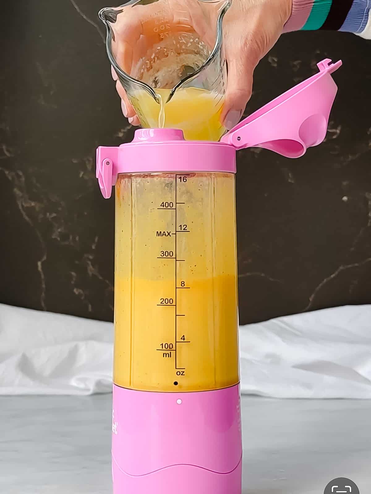 Pouring hot butter into a blender with other ingredients to make hollandaise sauce.