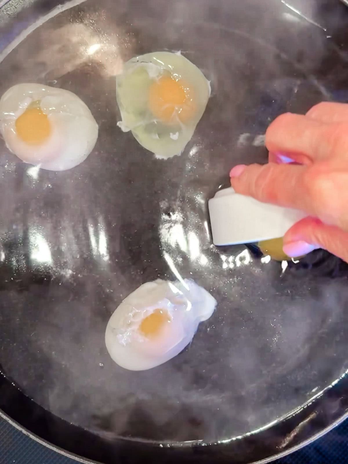 Placing raw eggs into very hot water to make no boil poached eggs.