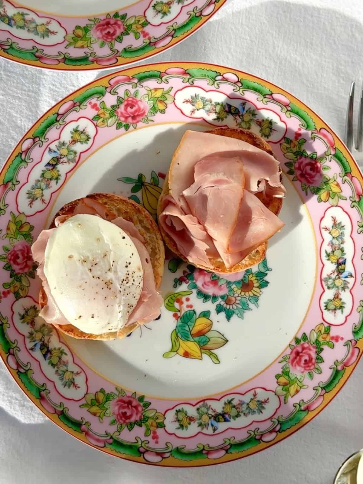 Placing ham and a poached egg on a toasted English muffin for eggs Benedict.