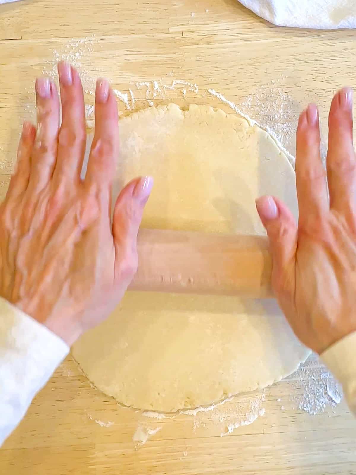 Using a rolling pan to roll out pie dough on a wooden counter.