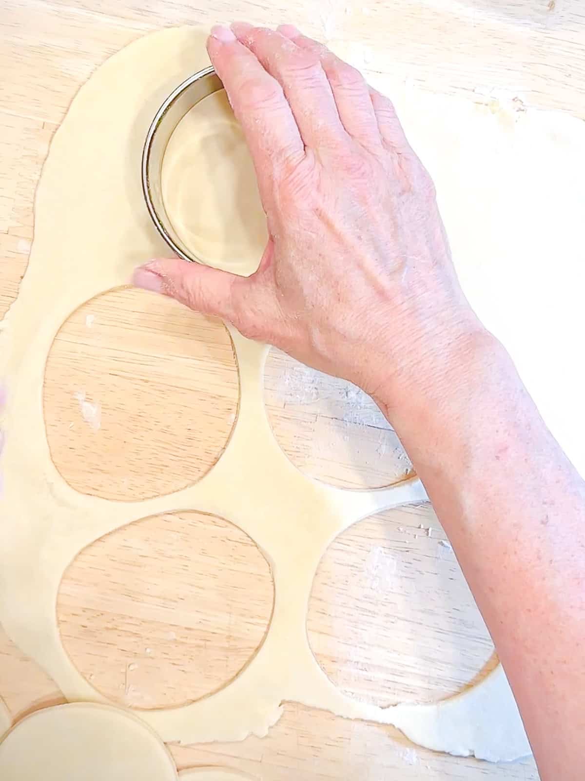 Using a large cookie cutter to cut out circles of pie dough.