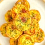 A stack of mini quiche Lorraine on a white plate with a tan rim.