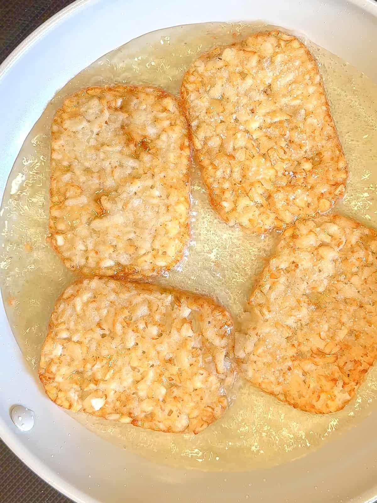 Shallow frying hash brown patties in a little bit of oil in a nonstick pan.