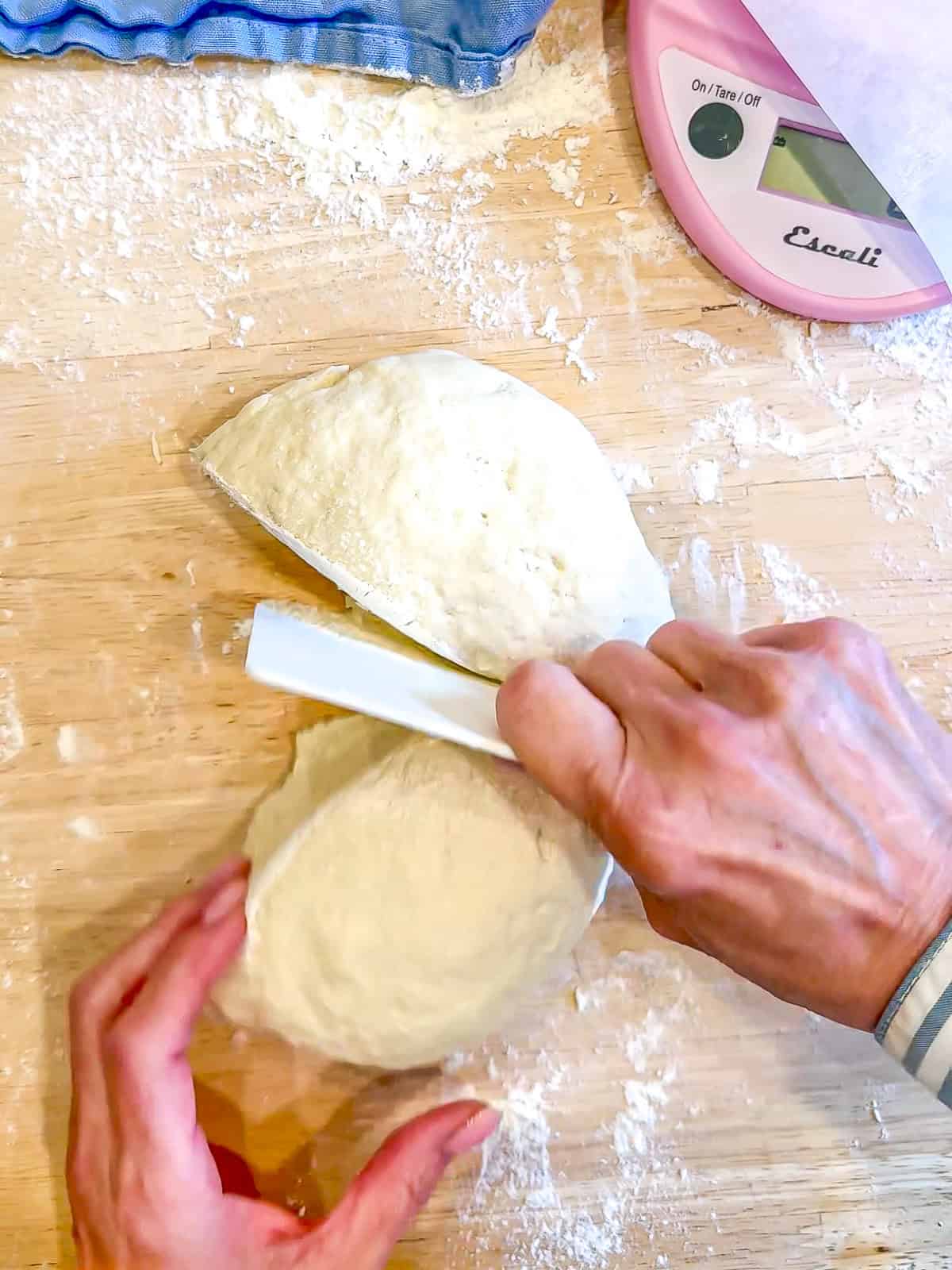 Cutting cottage cheese bagel Joe with a flexible dough scraper.