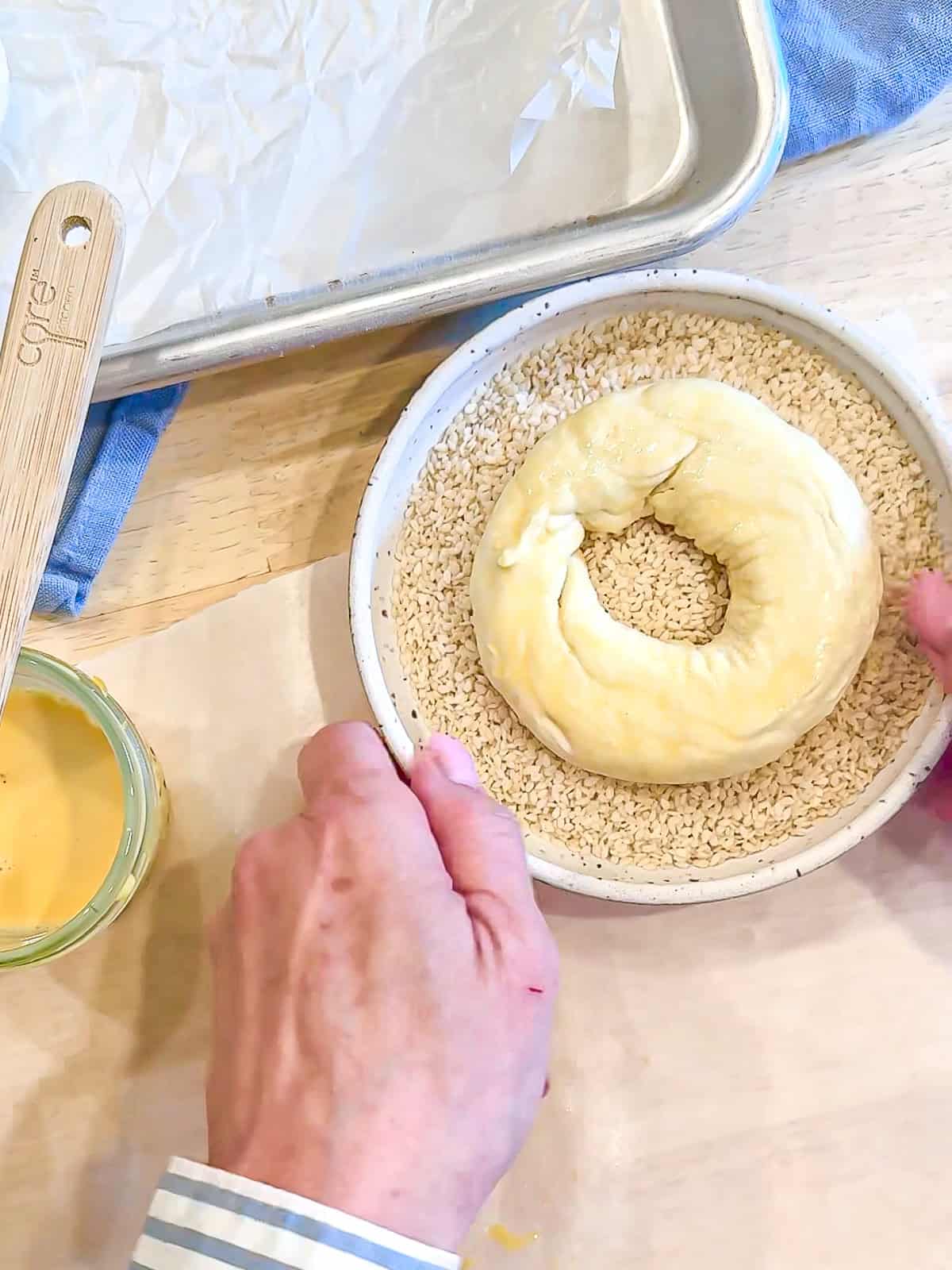 Adding sesame seed topping to a cottage cheese bagel.