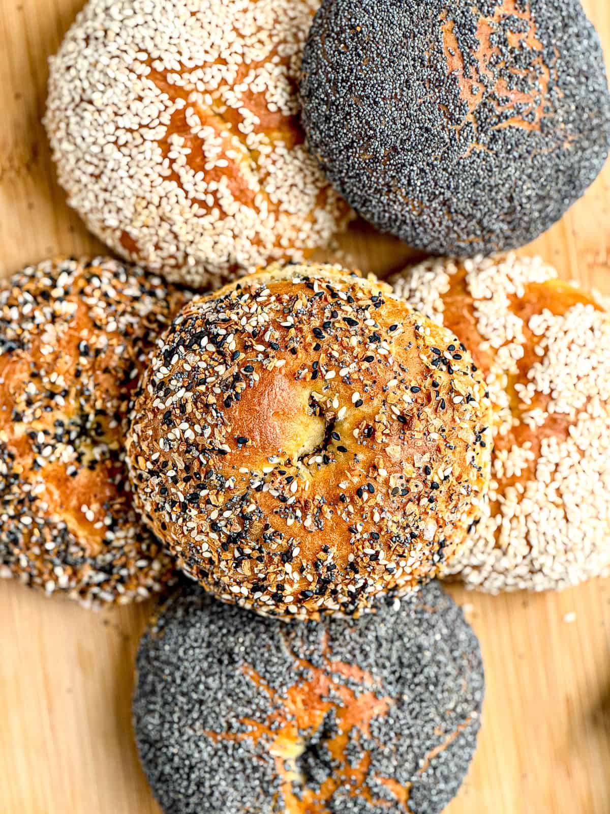 A stack of cottage cheese bagels with various toppings; sesame seeds, poppy seeds, and everything bagel seasoning.