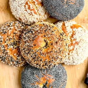 A stack of cottage cheese bagels with various toppings; sesame seeds, poppy seeds, and everything bagel seasoning.