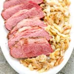 A platter containing slices of crispy corned beef and sautéed southern fried cabbage.