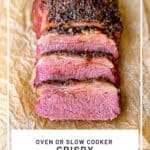 Pinterest image of a sliced crispy corned beef on a parchment paper covered cutting board.