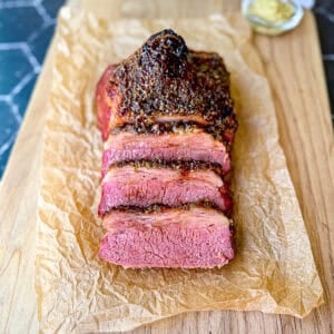 Sliced crispy corned beef on a wooden cutting board.