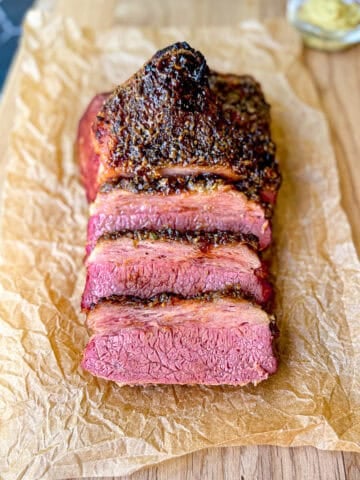 Sliced crispy corned beef on a wooden cutting board.