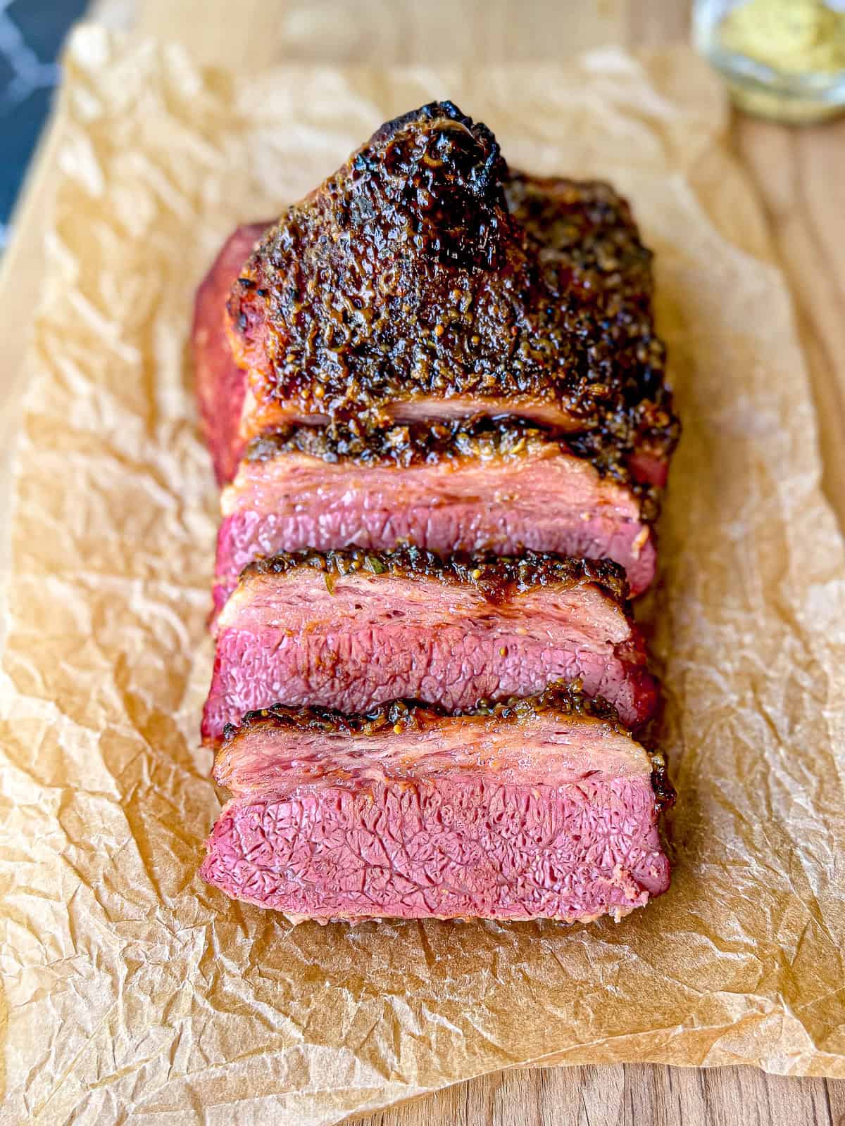 Sliced crispy corned beef on a wooden cutting board.