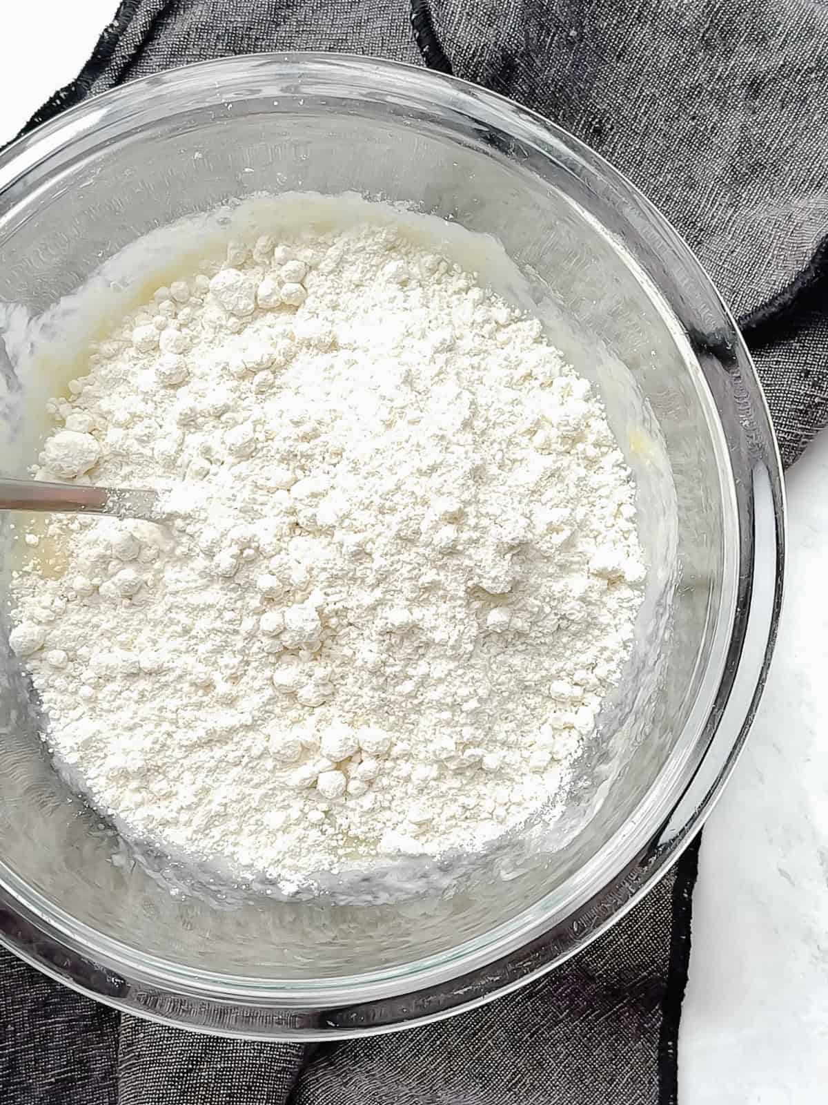 Adding baking mix to wet ingredients to make four ingredient eggless muffins.