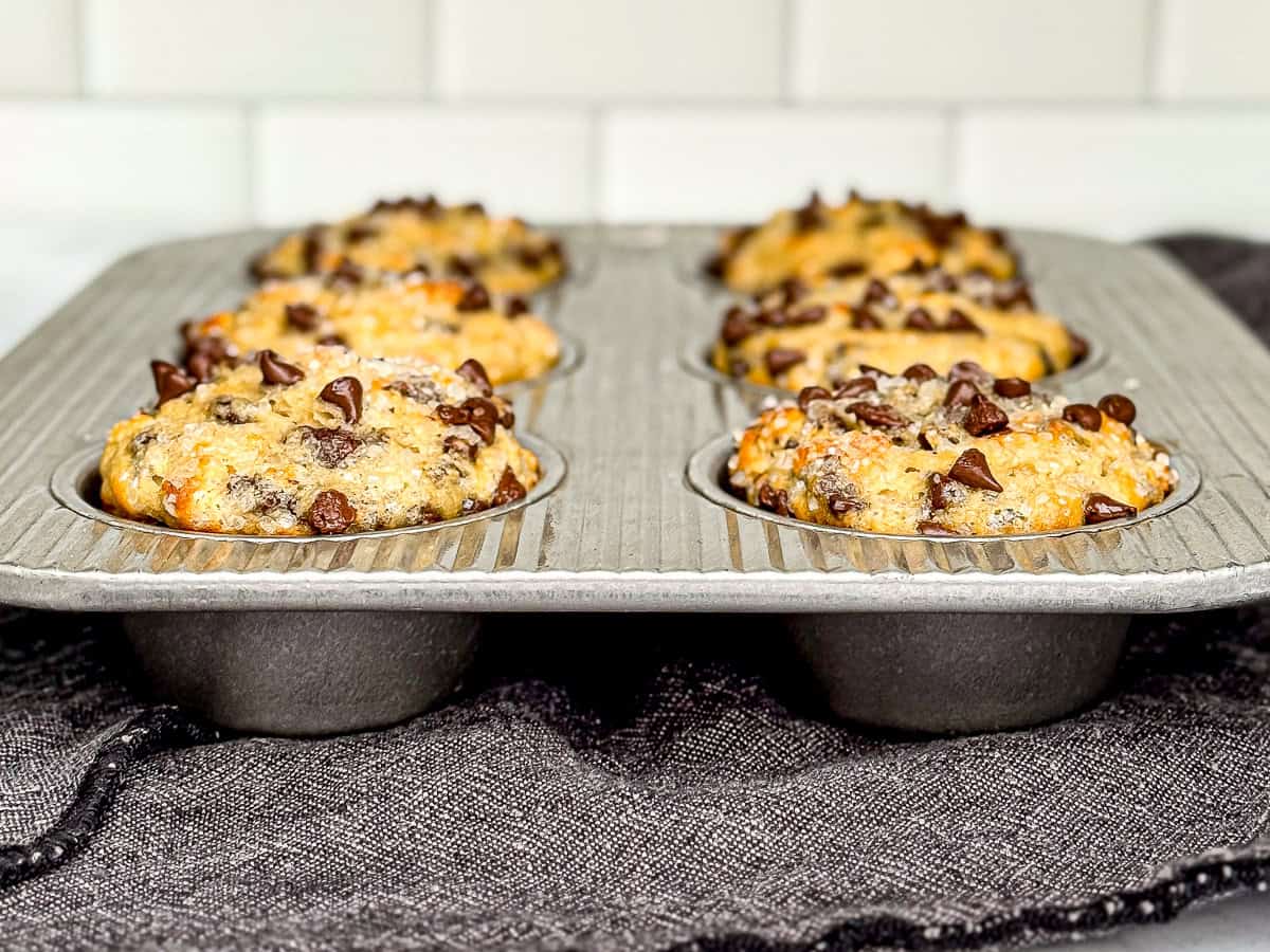 Side view of a muffin pan with four ingredient eggless muffins inside.