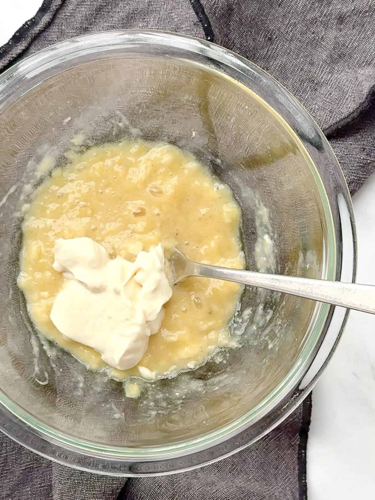 Stirring yogurt into mashed banana to make eggless banana muffins with only four ingredients.