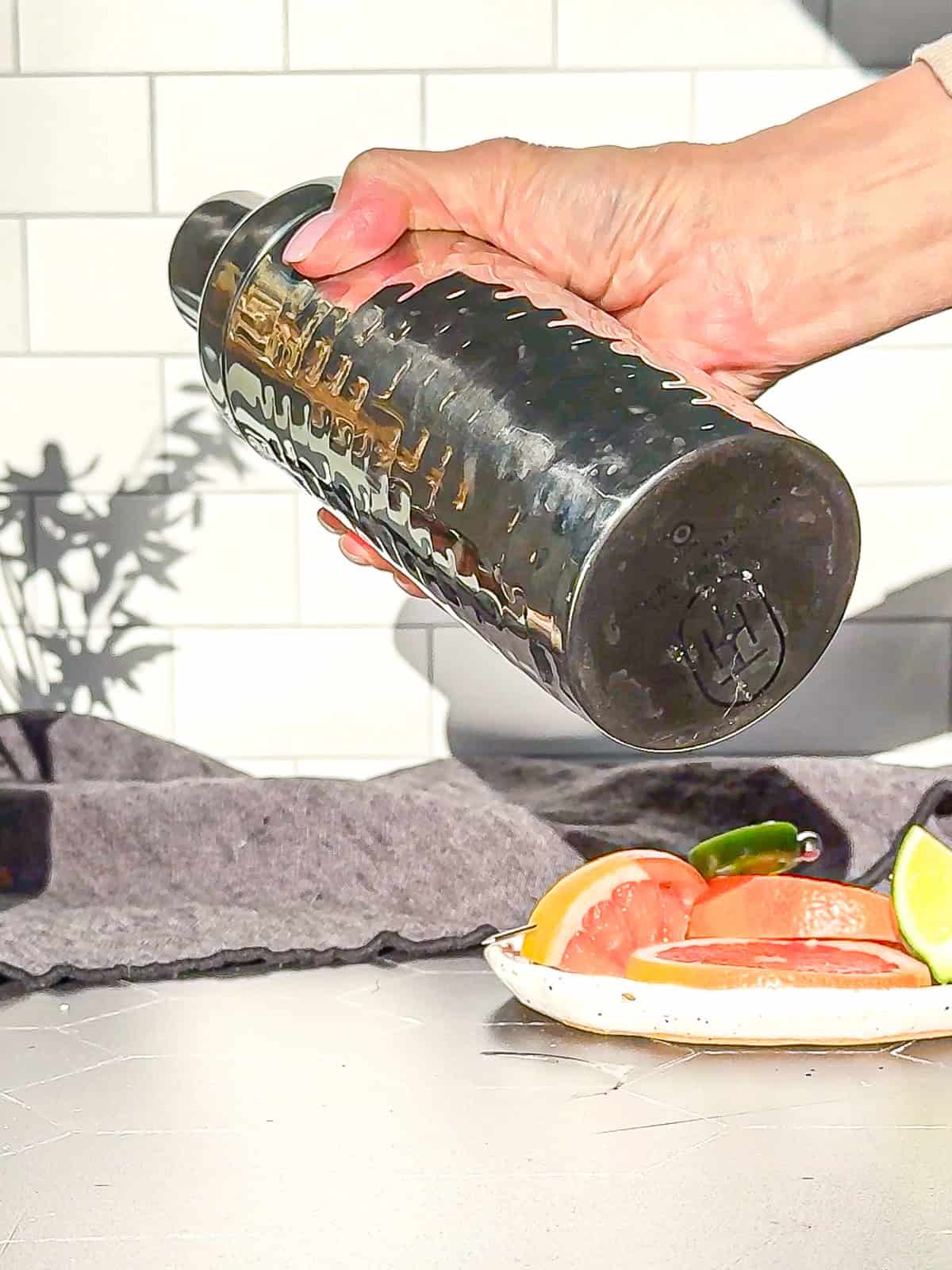 Shaking the base ingredients for a spicy Paloma Mocktail in a cocktail shaker.