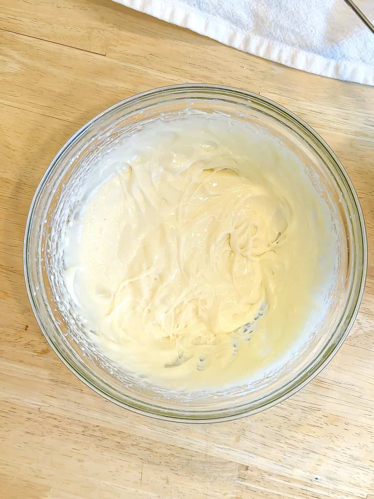 Cream cheese frosting in a glass bowl.