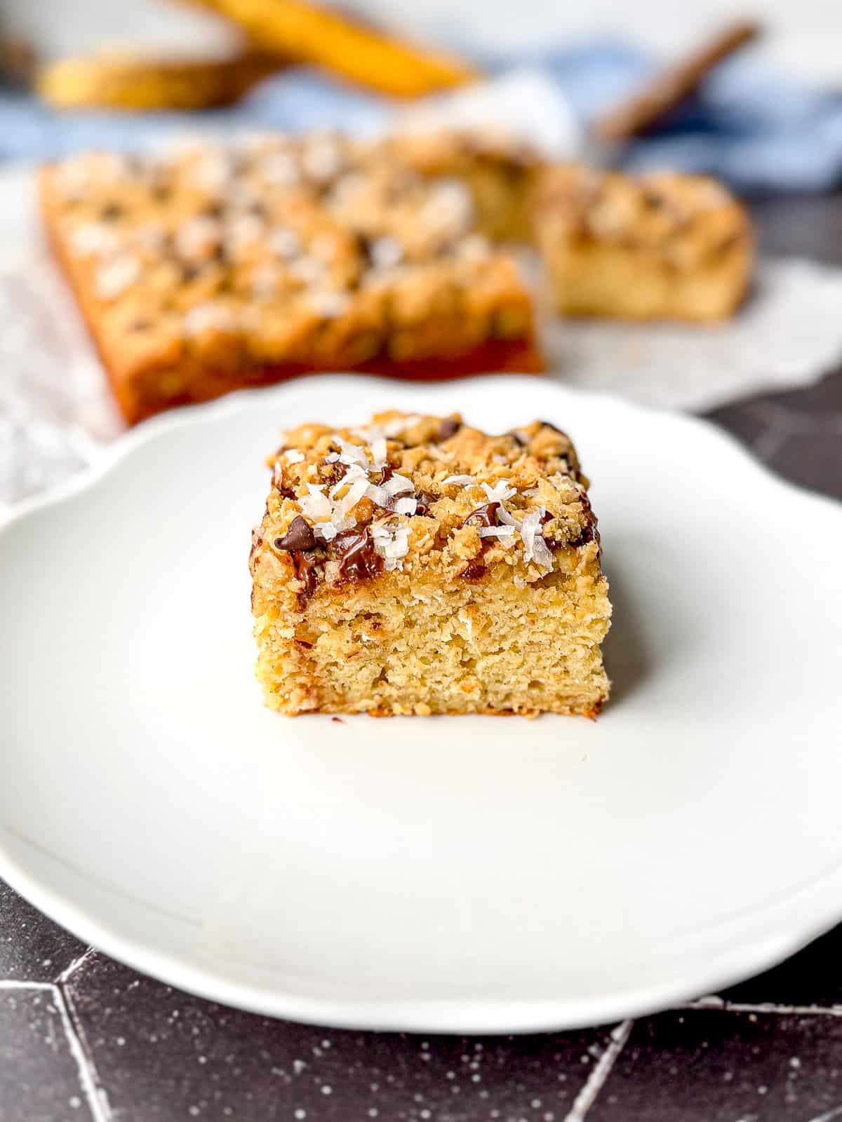 A square slice of banana breakfast cake on a white plate.