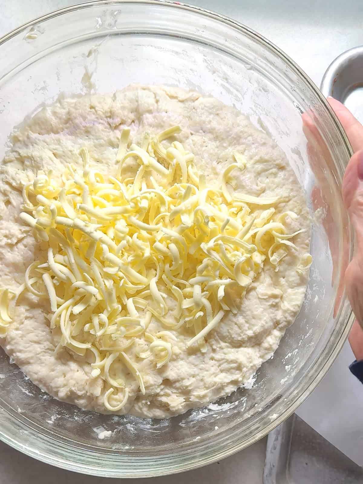 Placing the first portion of grated frozen butter in the center of bulk fermented no knead dough.