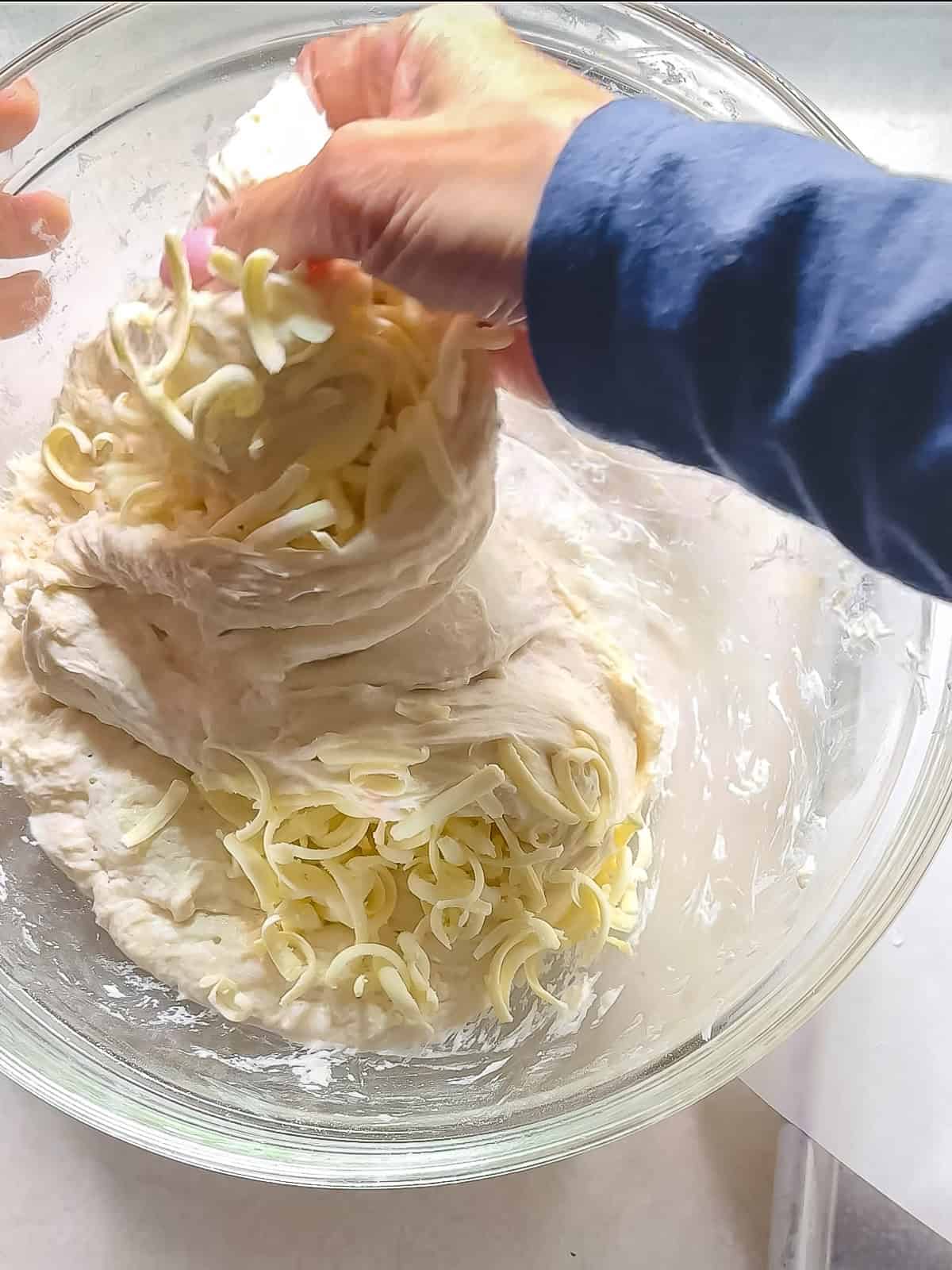 Folding no knead bread dough over shredded frozen butter to enclose it.