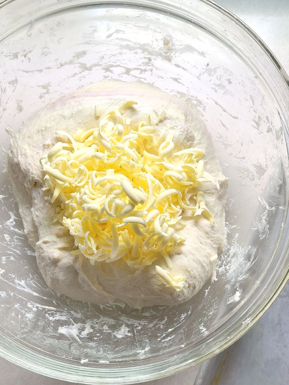 Placing shredded frozen butter in the center of a ball of dough to laminate it.