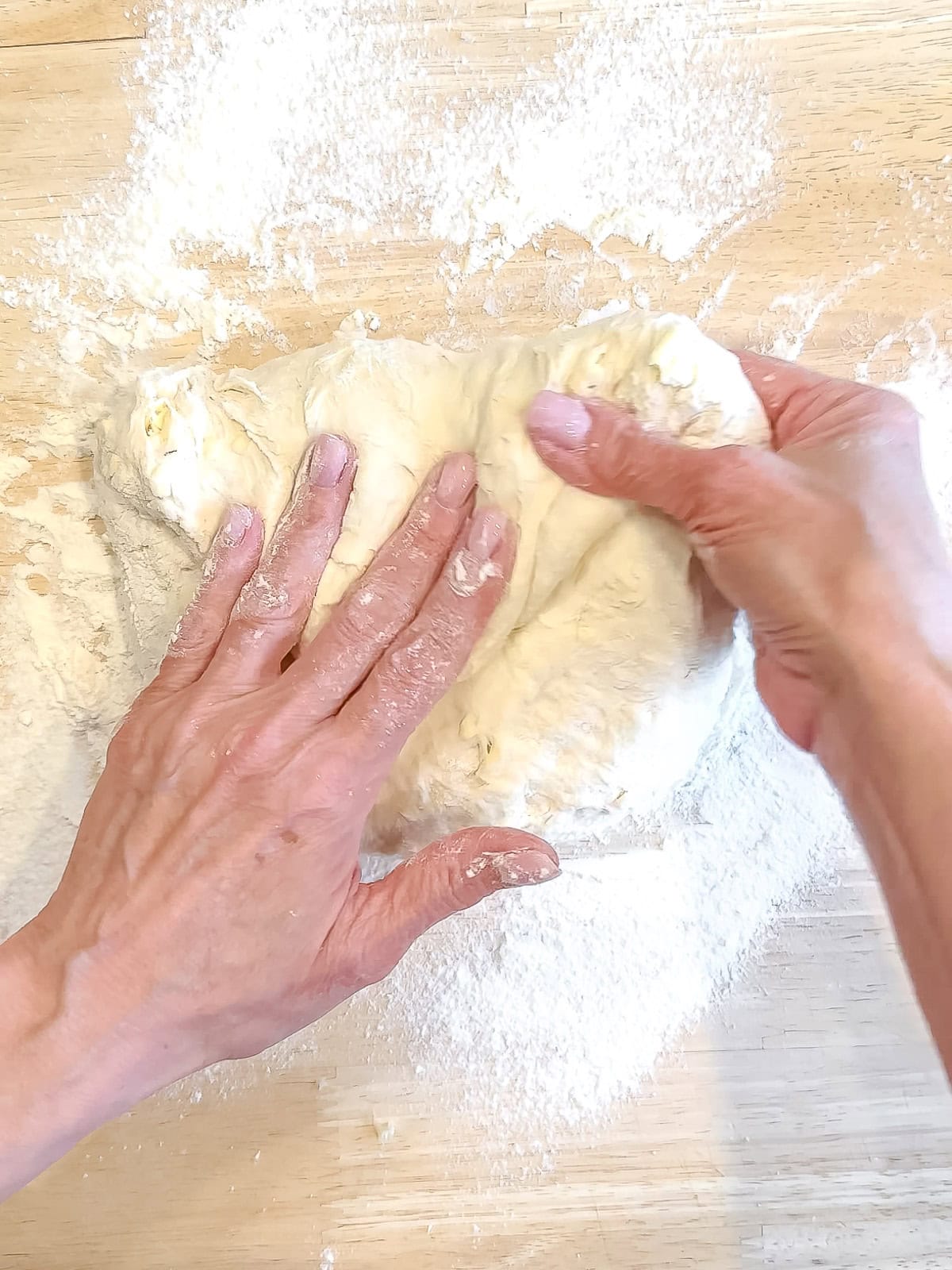 Folding the top of a circle of dough down to the center to start forming a ball.