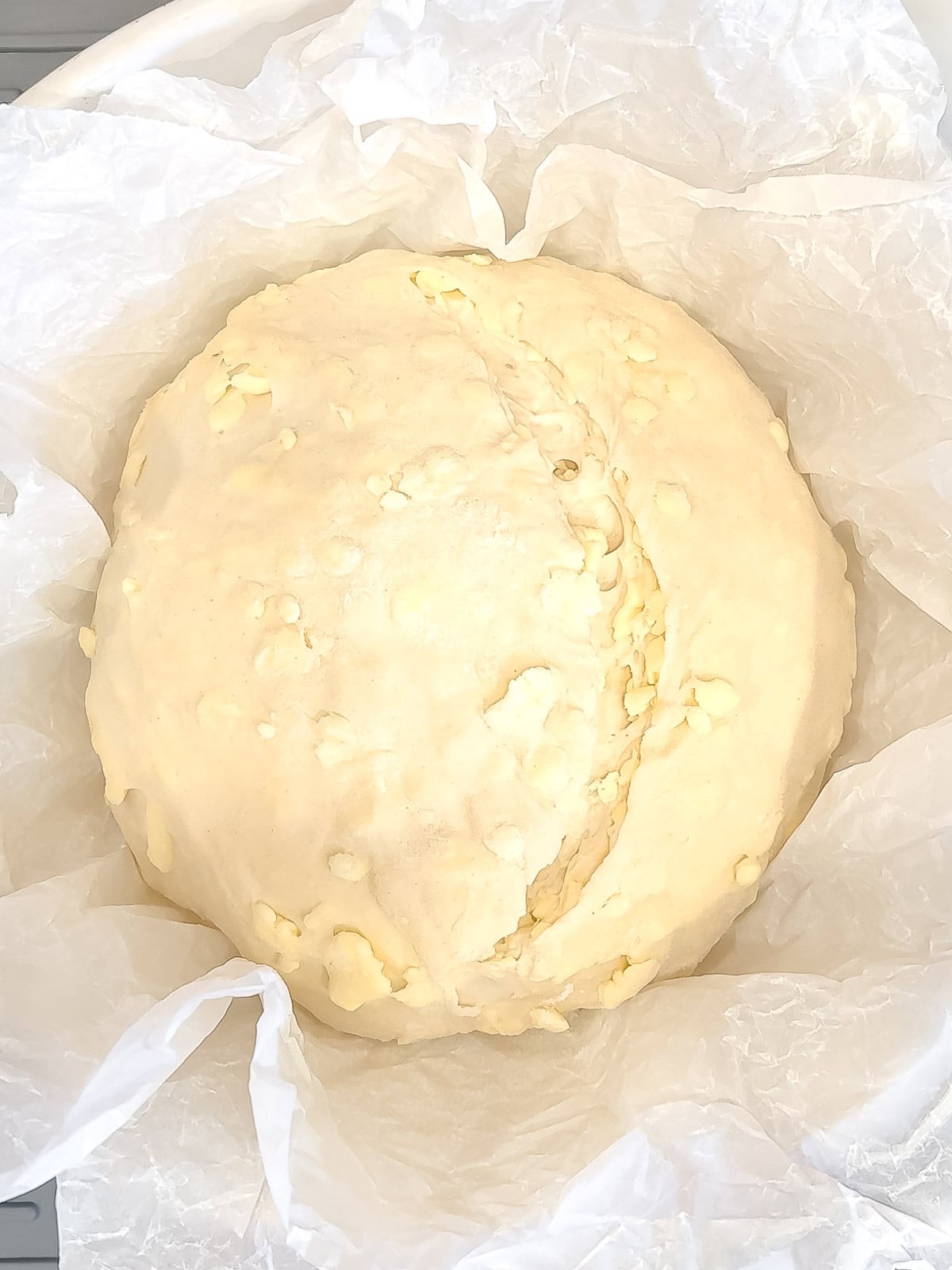 Croissant bread loaf in a bread Baker, scored on the top.