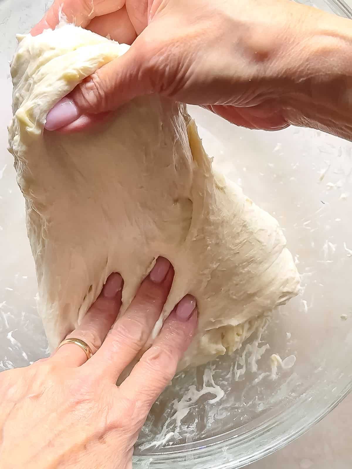 Doing the fourth fold of no knead croissant bread, using second hand to assist in stretching the dough.