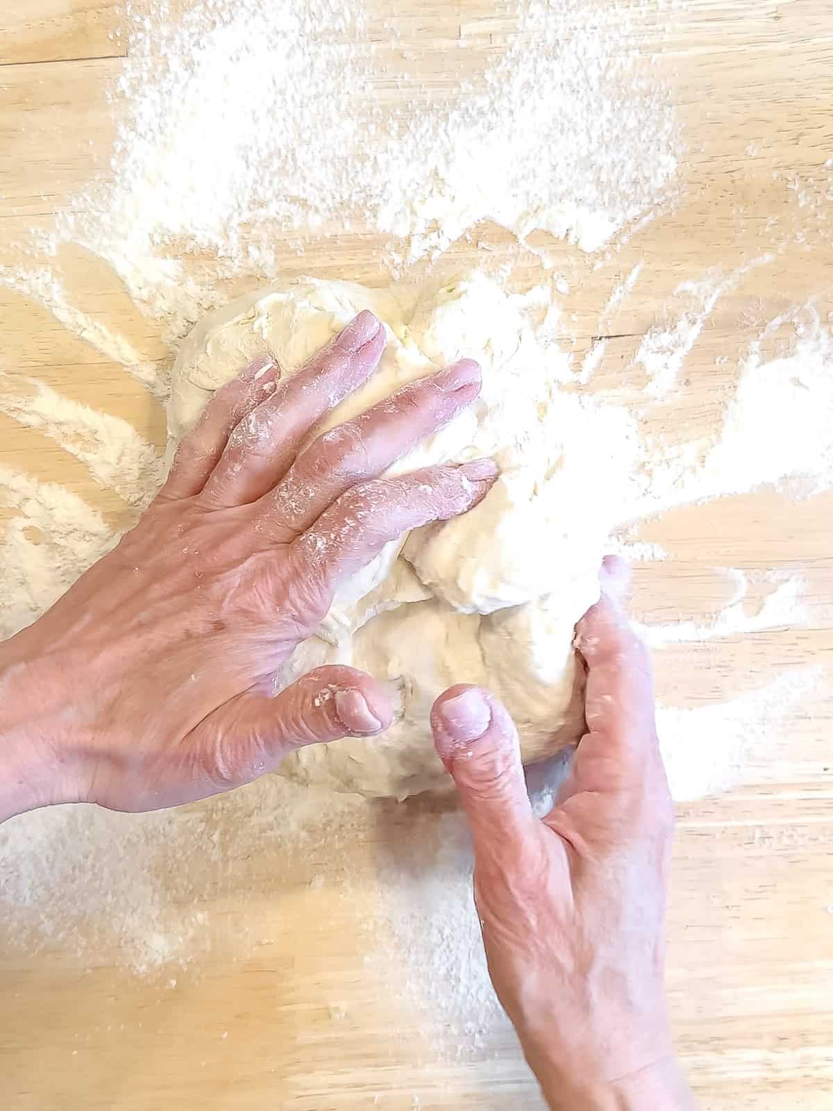 Folding side up and over to the center of a dough ball to form its round shape.
