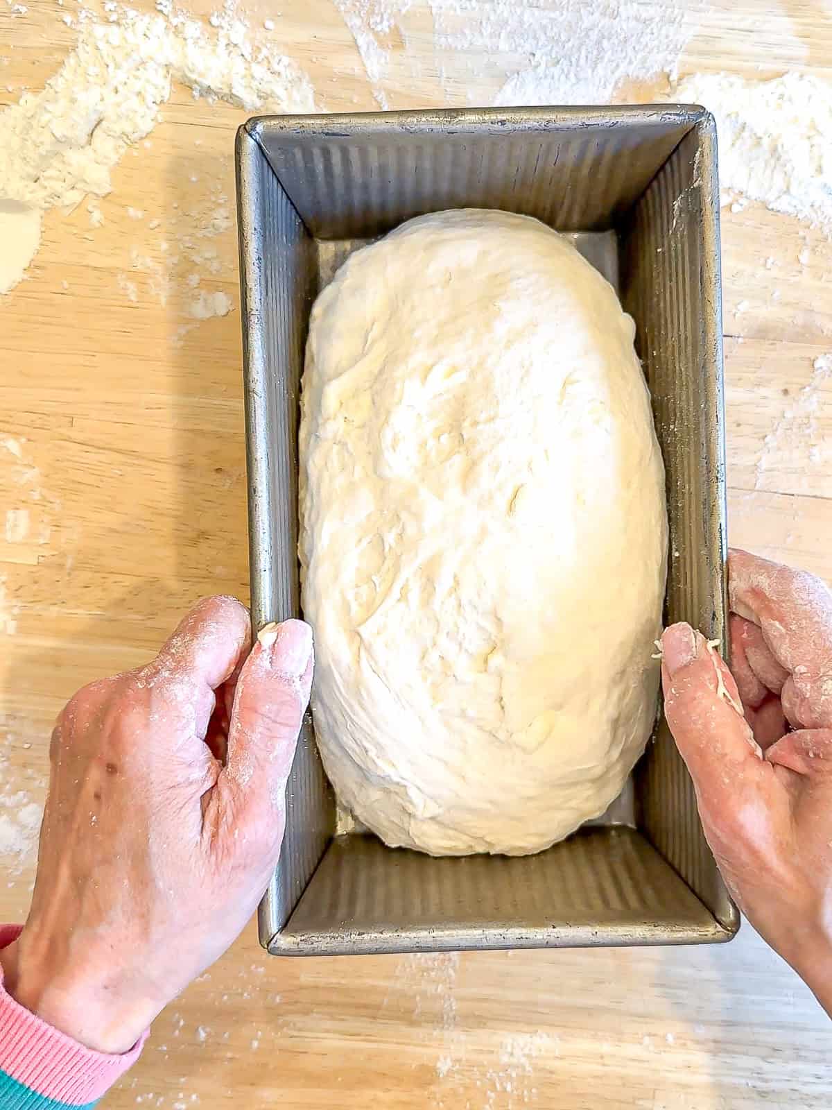 Placing bread dough into a bread pan.