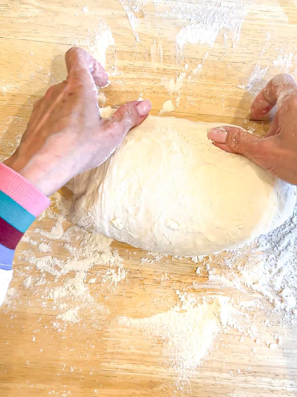 Shaping a loaf of bread into a log shape.