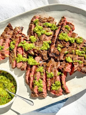 Image of Italian skirt steak on a grey platter covered in Italian chimichurri.